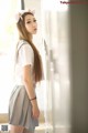 A woman in a white shirt and gray skirt posing for a picture.