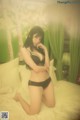 A woman in a black lingerie sitting on a bed.