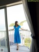 A woman in a blue dress standing on a balcony.