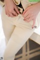 A woman in a beige suit is putting on her pants.