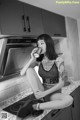 A woman sitting on a kitchen counter drinking from a can.