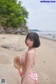 A woman in a red and white bikini standing on a beach.