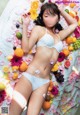 A woman laying on a bed covered in fruit and flowers.