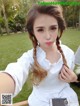 A woman in a white shirt is taking a selfie.