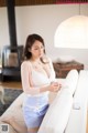 A woman sitting on a white couch in a living room.