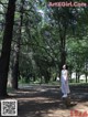 A woman standing on a tree stump in a park.