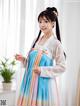 A woman in a blue and pink hanbok is posing for a picture.