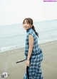 A woman standing on a beach next to the ocean.