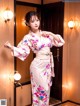 A woman in a pink kimono standing in front of a door.