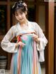 A woman in a blue and pink hanbok is posing for a picture.