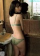 A woman in a green lingerie standing in front of a mirror.