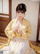 A woman in a yellow and white kimono sitting on the floor.