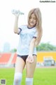 A woman in a soccer uniform holding a bottle of water.