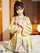 A woman in a yellow kimono posing on a bed.